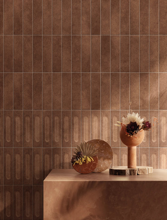 Brickworks Rosso Matt Decor 60x240mm tiles installed on a feature wall in warm terracotta tones, styled with a sculptural vase and dried floral arrangement on a marble console.