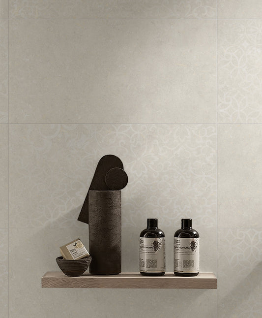 Brighton Beige Matt 600x600mm wall tiles with subtle damask pattern styled behind a wooden shelf displaying bath products and dark ceramic accessories.