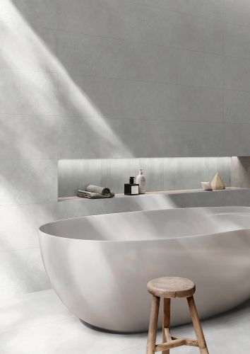 Brighton Bianco Matt 300x600mm light grey wall tiles installed in a minimalist bathroom featuring a freestanding oval bath and timber stool.
