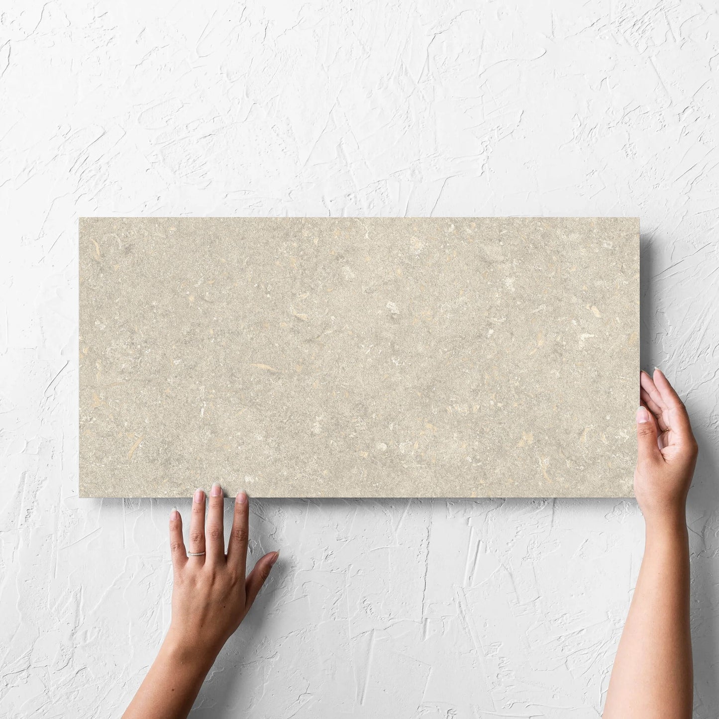 Hand holding a single Brighton Earth Matt 300x600mm tile against a white rendered wall, showing the matt surface