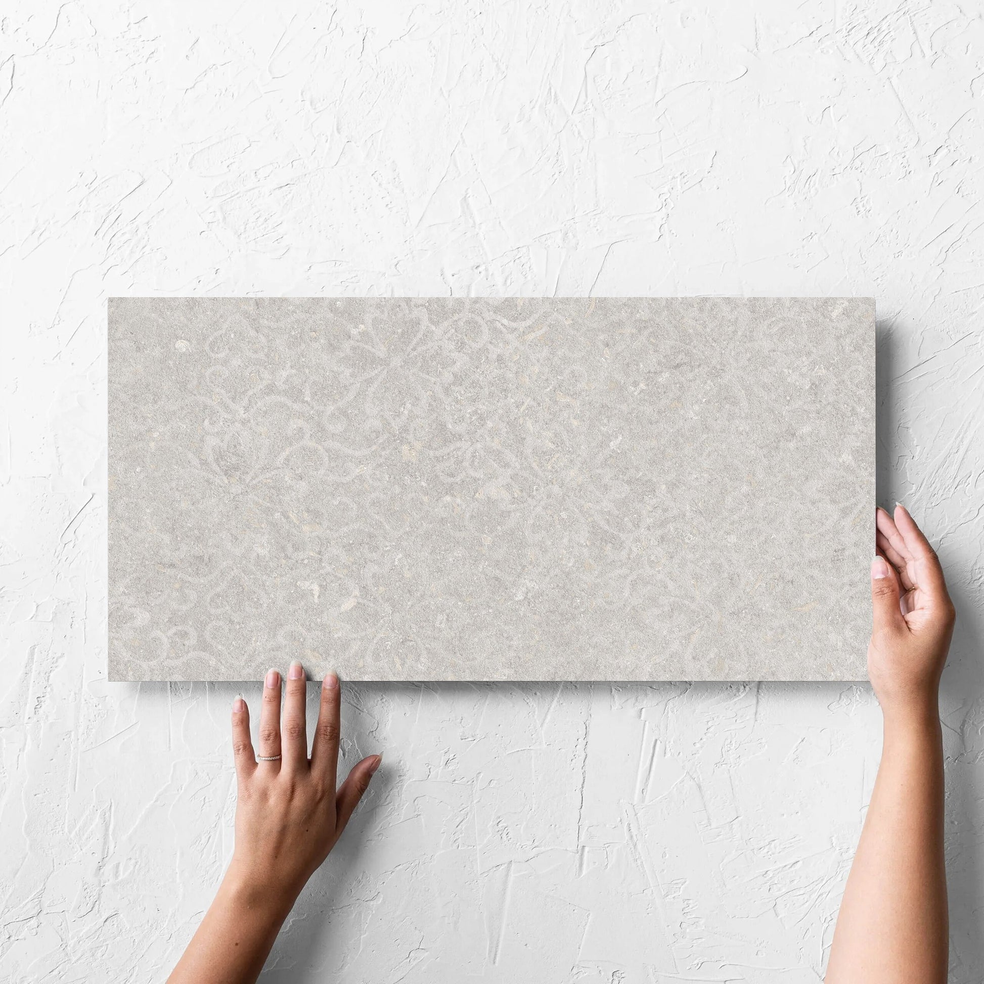 Hand holding a single Brighton Stone Matt 300x600mm tile against a white rendered wall, showing the matt surface