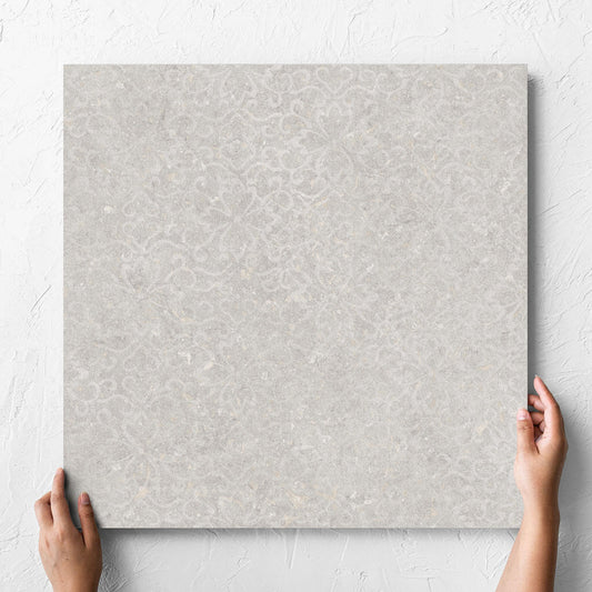 Hand holding a single Brighton Stone Matt 600x600mm tile against a white rendered wall, showing the matt surface