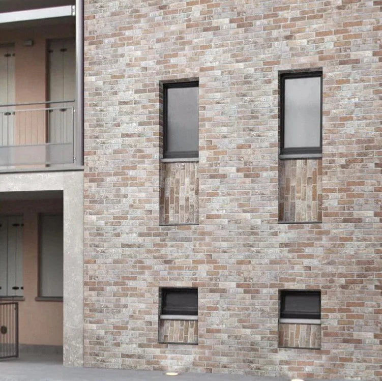 Bristol Rust Brick Tile 60x250mm installed on a contemporary exterior building facade with narrow black-framed windows and balcony detail.