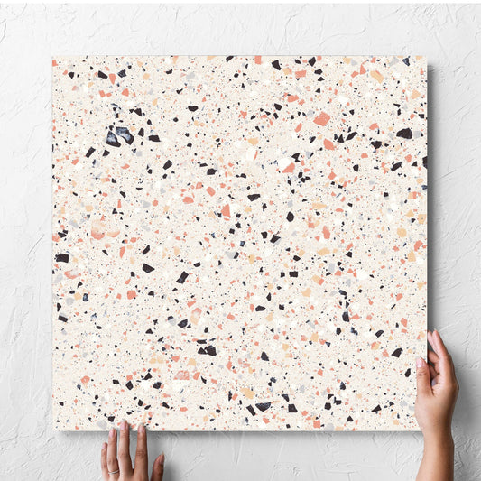 Hand holding a single C Venice 600x600 Matt Pink Terrazzo Look Rectified tile against a white rendered wall, showing the pink matt surface