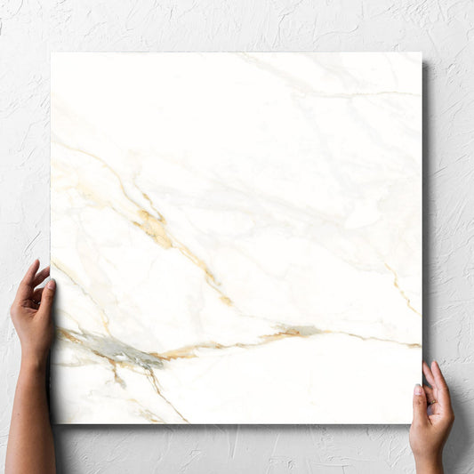 Hand holding a single Calacatta Vagli Matt 600x600mm tile against a white rendered wall, showing the tile surface
