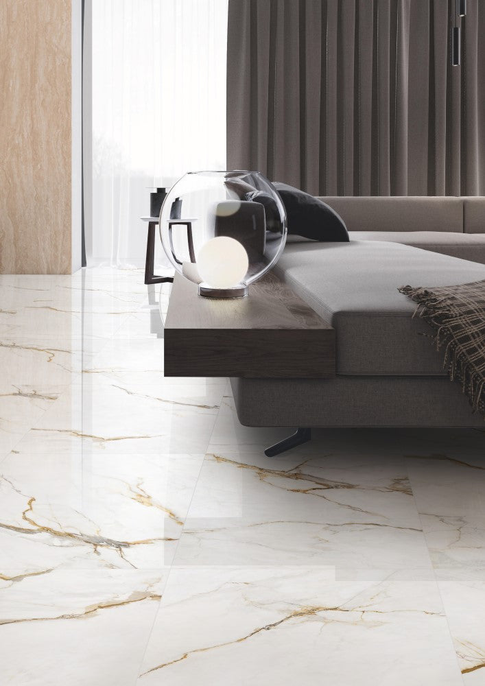 Calacatta Vagli Polished 600x600mm floor tiles installed in a luxury bedroom with grey upholstered sofa, dark wood console, and globe table lamp.