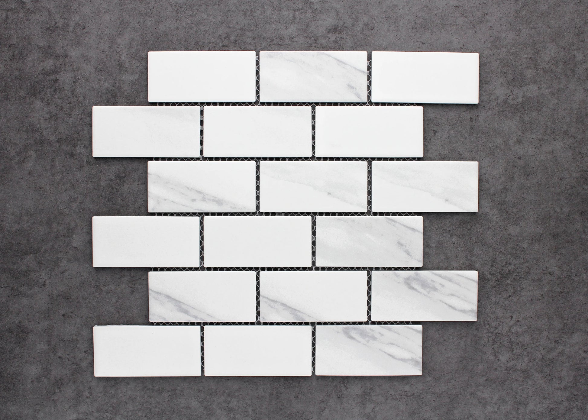 Pack shot of Carrara Look Matte Porcelain Glazed Brickbone 45x95mm tiles arranged in a classic brick-bond pattern, showing white matte finish with subtle grey marble veining.