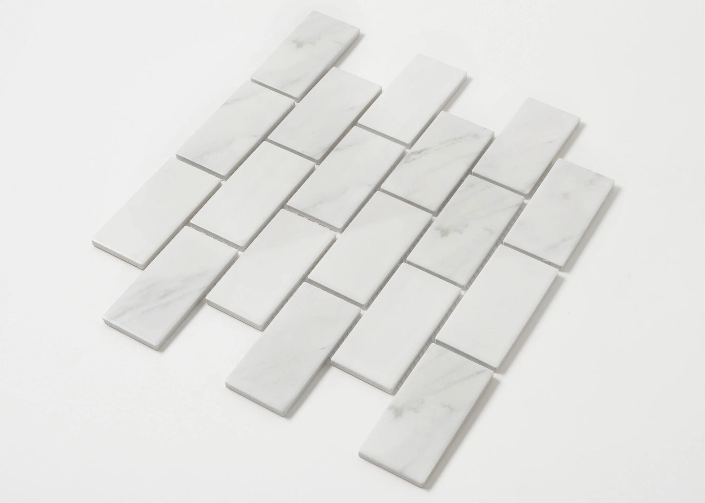 Pack shot of Carrara Look Matte Porcelain Glazed Brickbone 45x95mm tiles arranged in a staggered brick-bond layout, showing white marble-look finish with subtle grey veining.