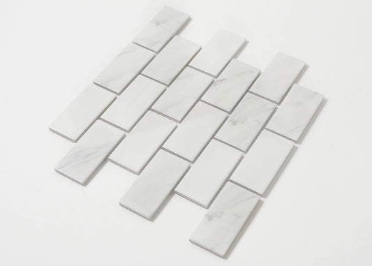 Pack shot of Carrara Look Matte Porcelain Glazed Brickbone 45x95mm tiles arranged in a staggered brick-bond layout, showing white marble-look finish with subtle grey veining.