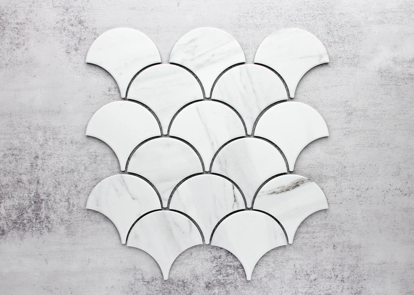 Pack shot of Carrara Look Matte Porcelain Glazed Fishscale 95x87mm tiles arranged in a scallop mosaic pattern, showing white marble-look finish with subtle grey veining.