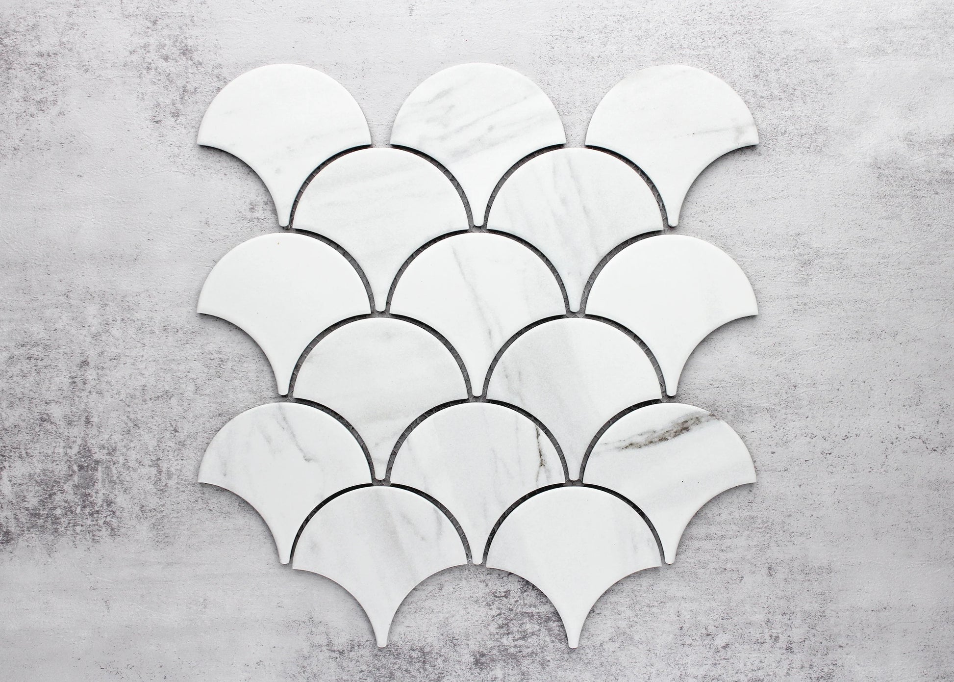 Pack shot of Carrara Look Matte Porcelain Glazed Fishscale 95x87mm tiles arranged in a scallop mosaic pattern, showing white marble-look finish with subtle grey veining.