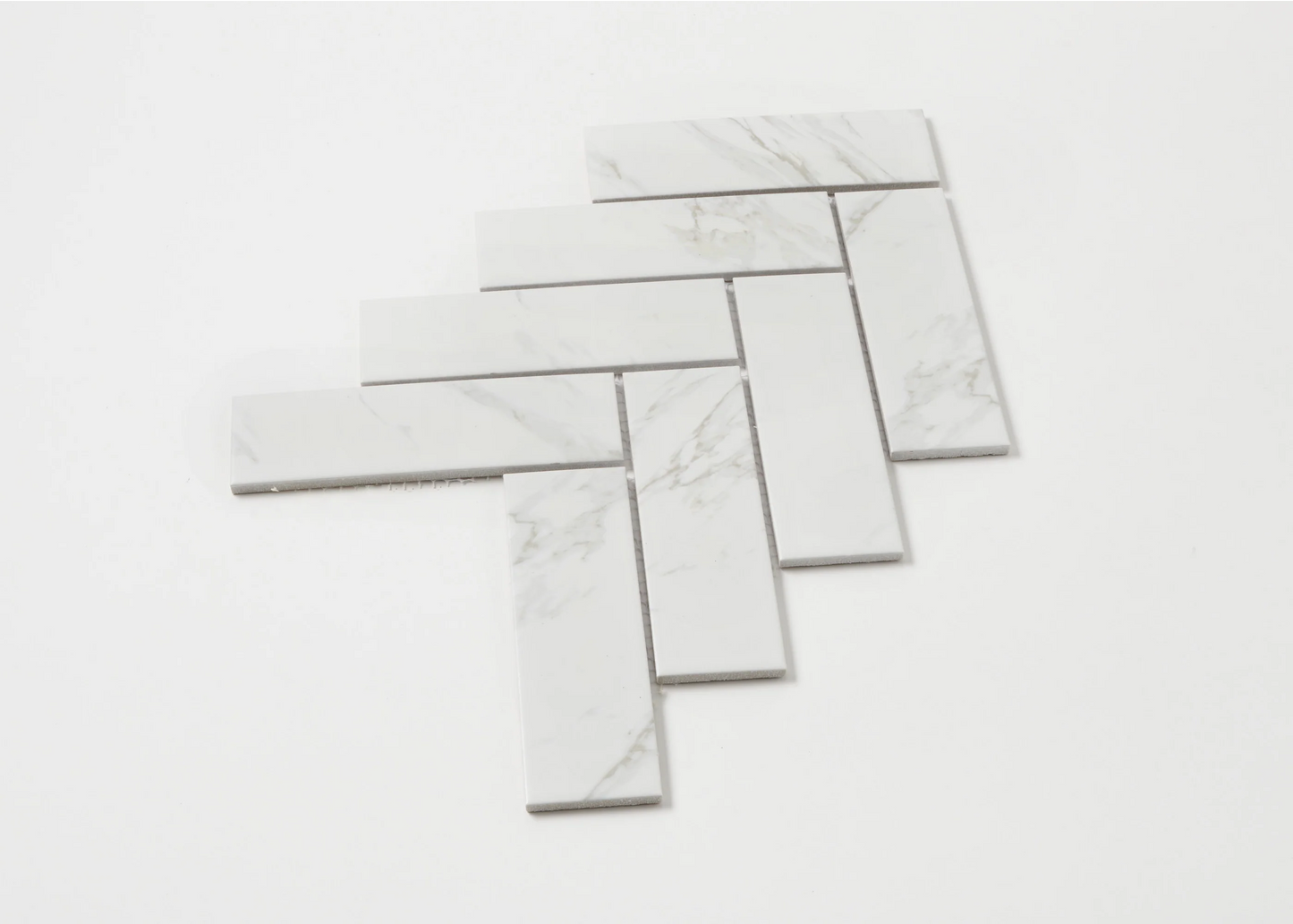 Carrara Look Matte Porcelain Glazed Herringbone 45x145mm tiles arranged in a fanned herringbone pattern showing white marble-look finish with subtle grey veining.