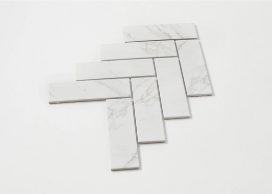 Carrara Look Matte Porcelain Glazed Herringbone 45x145mm tiles arranged in a fanned herringbone pattern showing white marble-look finish with subtle grey veining.