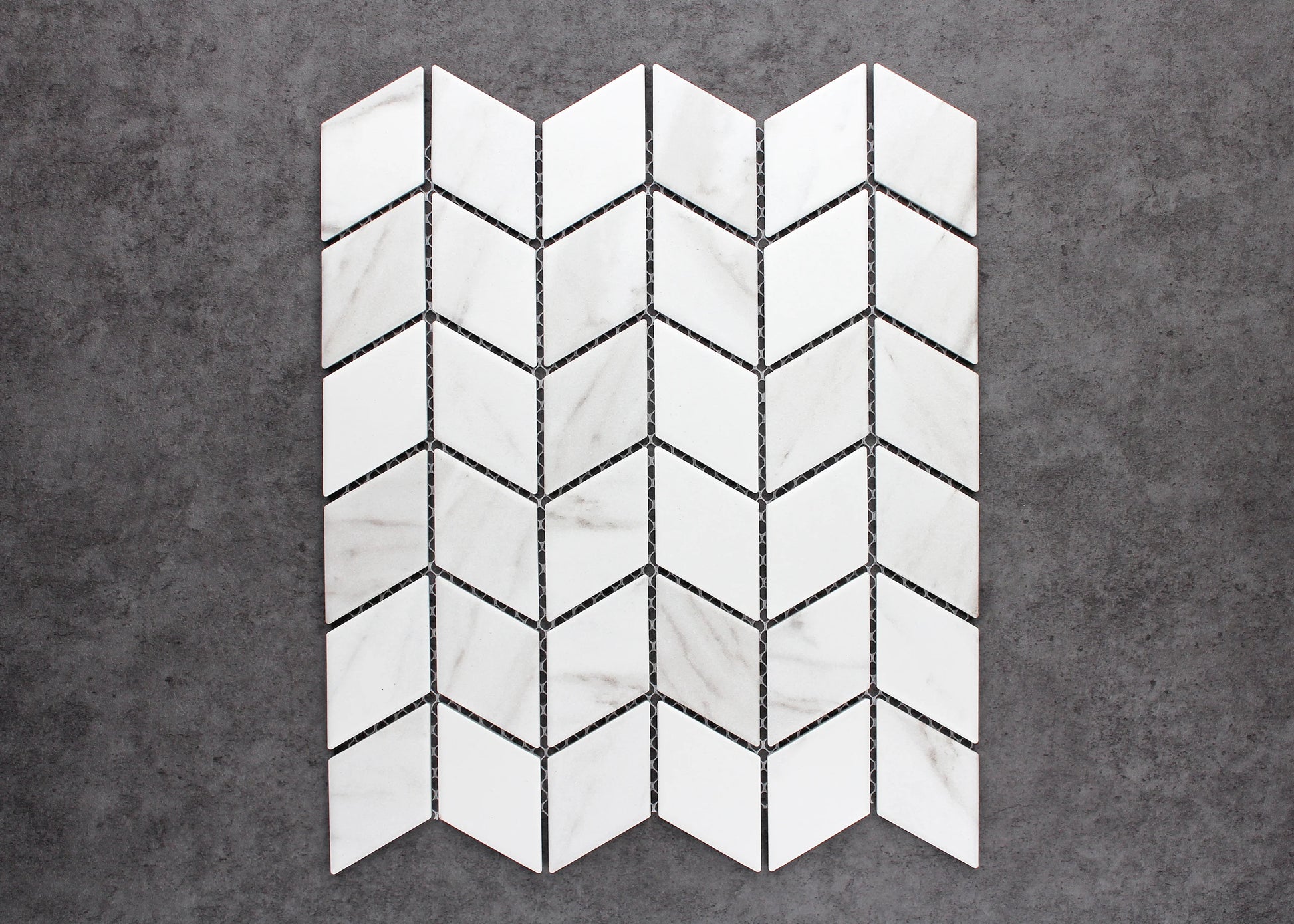 Pack shot of Carrara Look Matte Porcelain Glazed Rhombus 48x48mm tiles arranged in a chevron pattern, showcasing white marble-look veining and matte finish.