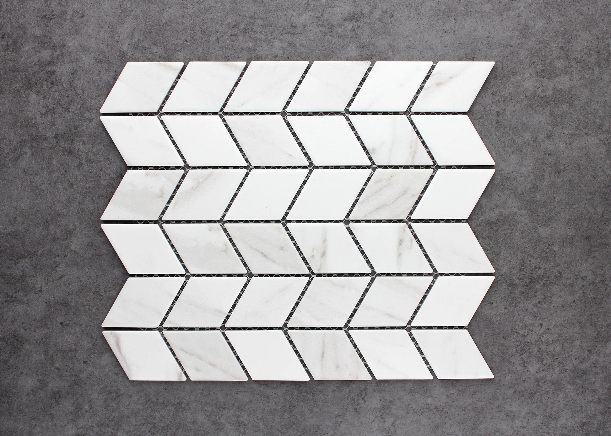 Pack shot of Carrara Look Matte Porcelain Glazed Rhombus 48x48mm tiles arranged in a chevron mosaic sheet pattern with white marble-look finish and grey veining.