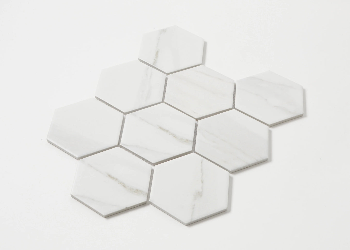Pack shot of Carrara Matte Porcelain Glazed Hexagon 95x110mm tiles arranged in a cluster, showcasing white marble-look finish with subtle grey veining.