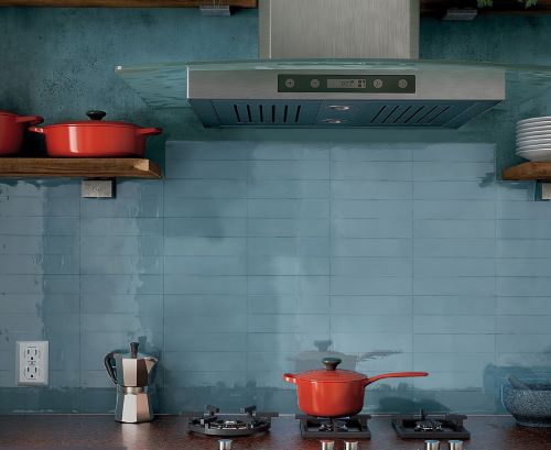 Casablanca Baby Blue Gloss 58x242mm tiles installed as a kitchen splashback behind a stainless steel range hood and gas cooktop with red cookware.