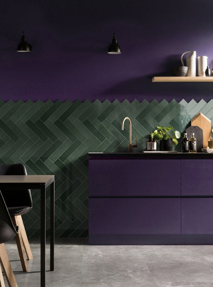 Casablanca Bottle Green Gloss 58x242mm tiles installed in a herringbone pattern kitchen splashback against deep purple cabinetry and walls.