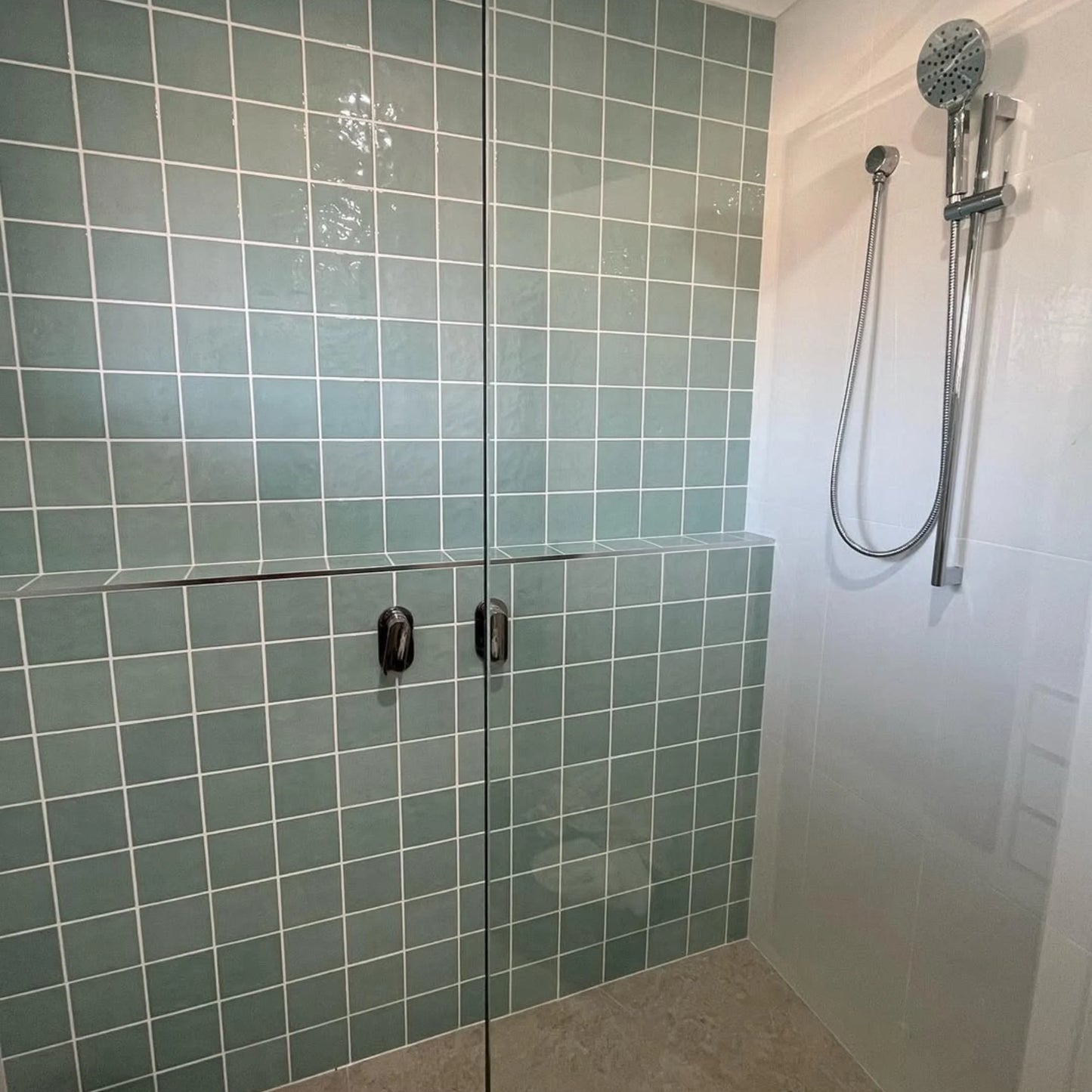 Casablanca Mint Gloss 120x120mm tiles covering a shower wall behind frameless glass doors with chrome handheld shower rail and white panel side wall.