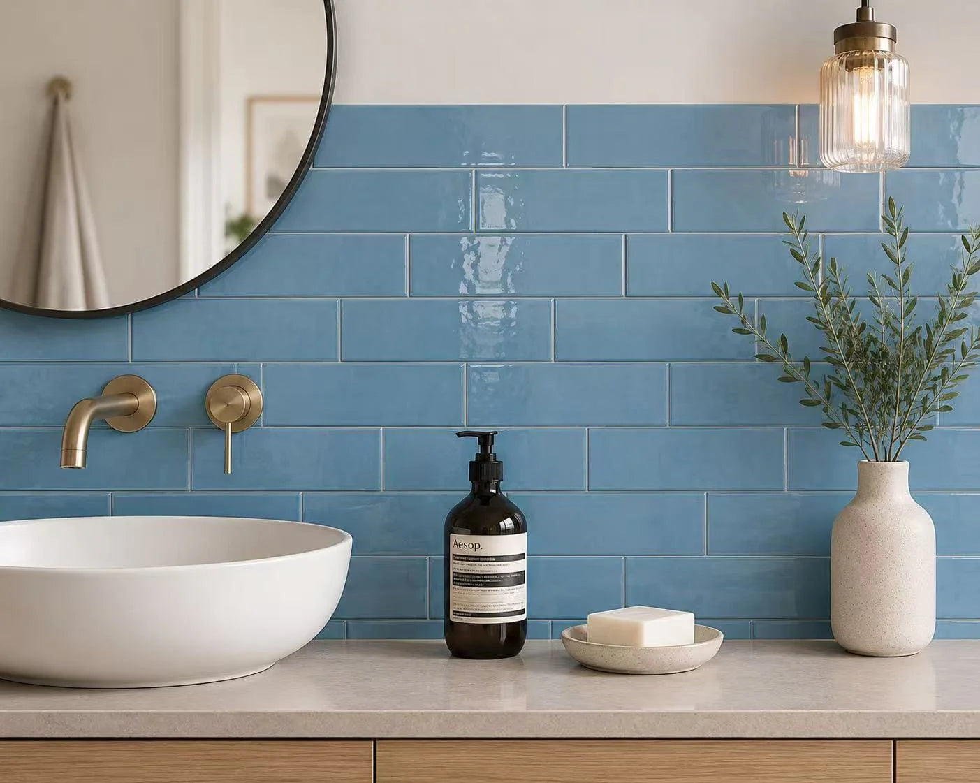 Casablanca Sky Blue Gloss 58x242mm subway tiles installed as a bathroom vanity splashback with brass wall-mount tap, round mirror, and pendant light.