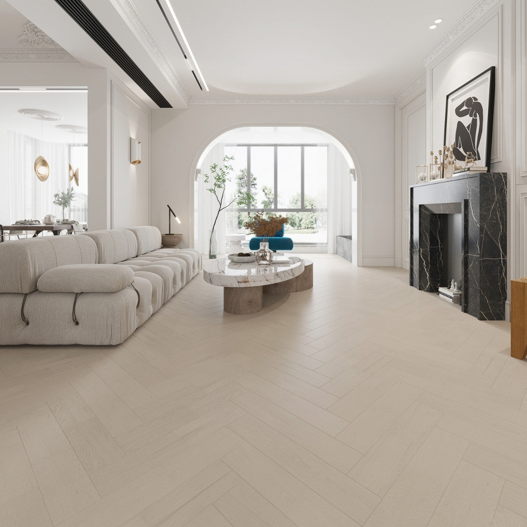 Casper White iDesign Chevron Flooring 15/3mm installed in a bright luxury living room featuring a tufted sofa, marble coffee table, and black marble fireplace.