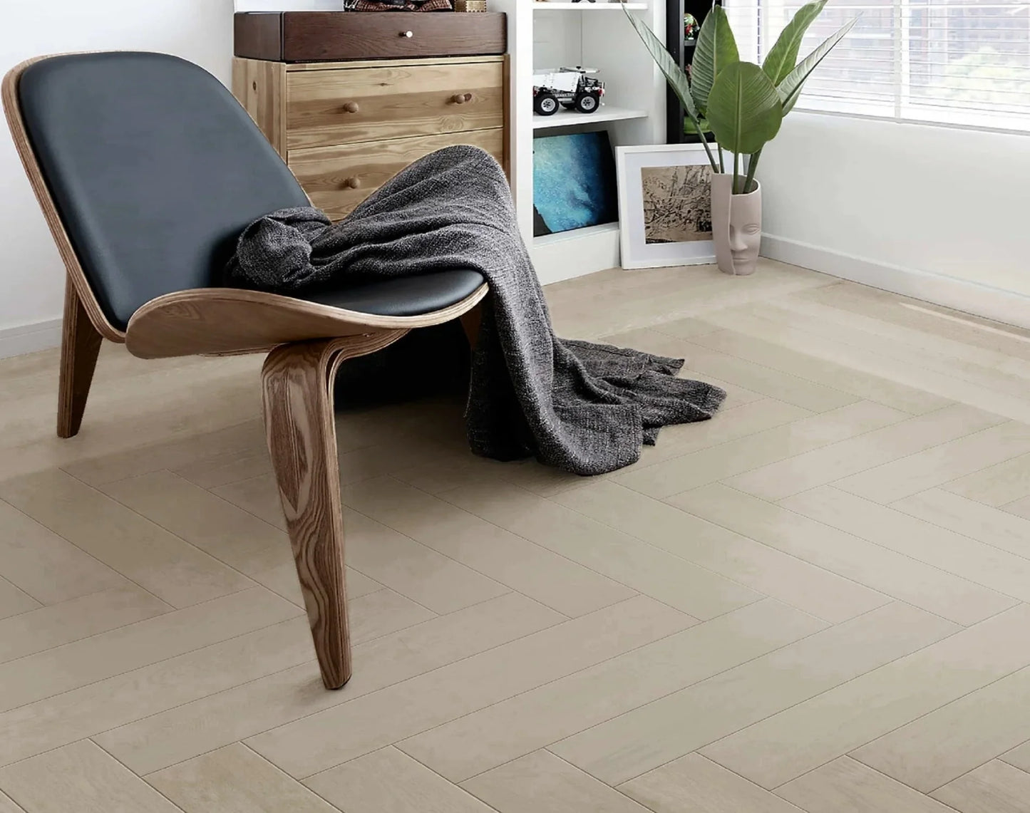 Casper White iDesign Herringbone Flooring 15/3mm installed in a modern bedroom with a sculptural wooden lounge chair, timber dresser, and indoor plant.