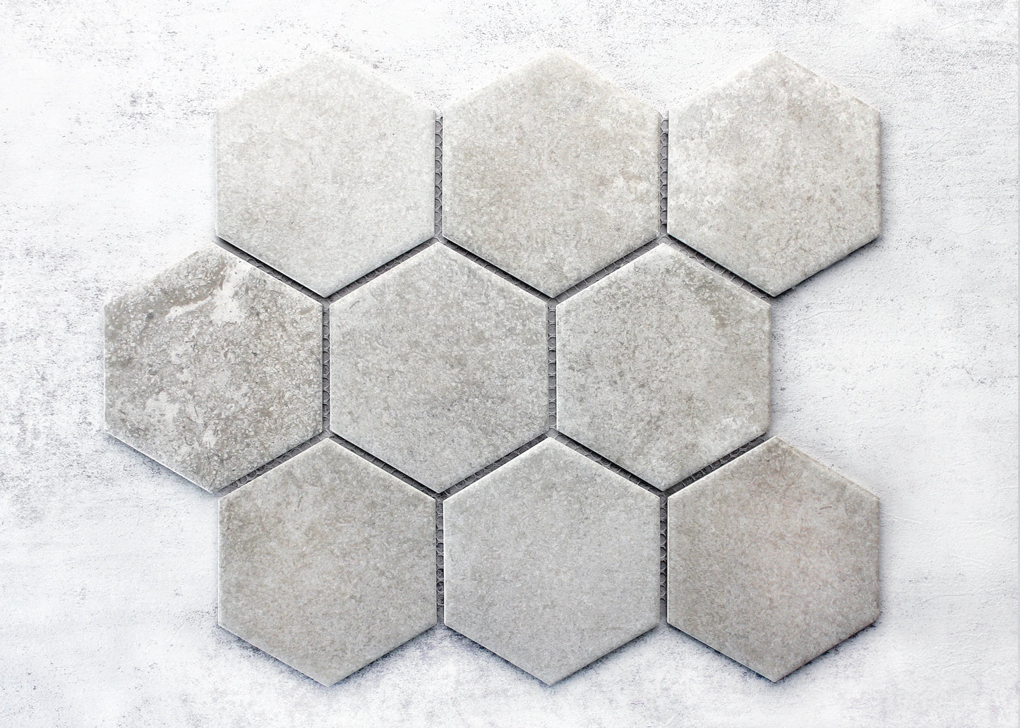 Pack shot of Cement Matte Porcelain Glazed Hexagon 95x110mm tiles arranged in a cluster, showing light grey matte finish with subtle stone-like texture variation.