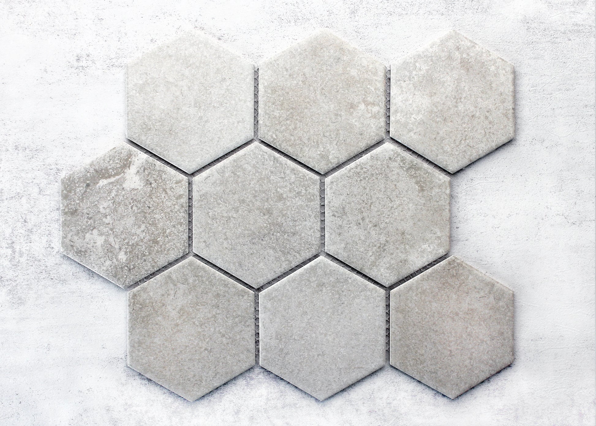Pack shot of Cement Matte Porcelain Glazed Hexagon 95x110mm tiles arranged in a cluster, showing light grey matte finish with subtle stone-like texture variation.