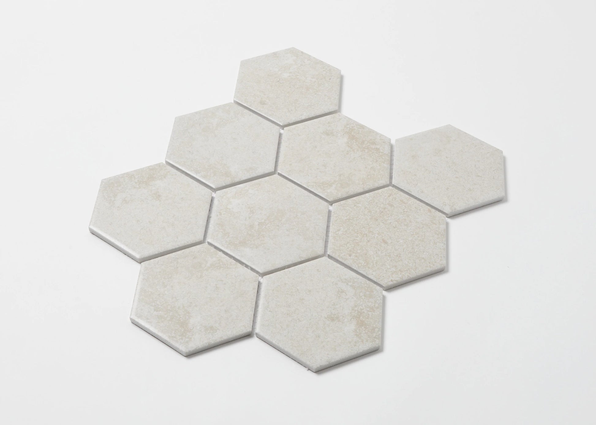 Pack shot of Cement Matte Porcelain Glazed Hexagon 95x110mm tiles arranged in a honeycomb cluster, showing a soft white matte finish with subtle texture variation.
