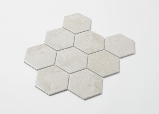 Pack shot of Cement Matte Porcelain Glazed Hexagon 95x110mm tiles arranged in a honeycomb cluster, showing a soft white matte finish with subtle texture variation.