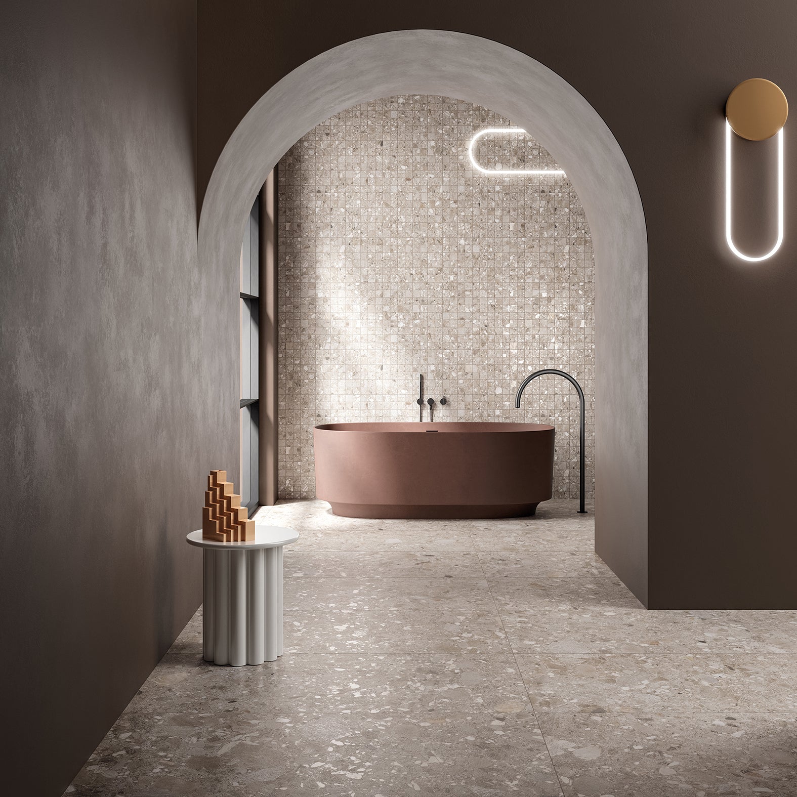 Ceppo Dark Beige InOut 600x600mm terrazzo-effect tiles covering the floor and mosaic feature wall of a luxurious arched bathroom with a freestanding terracotta bathtub and sculptural wall light.
