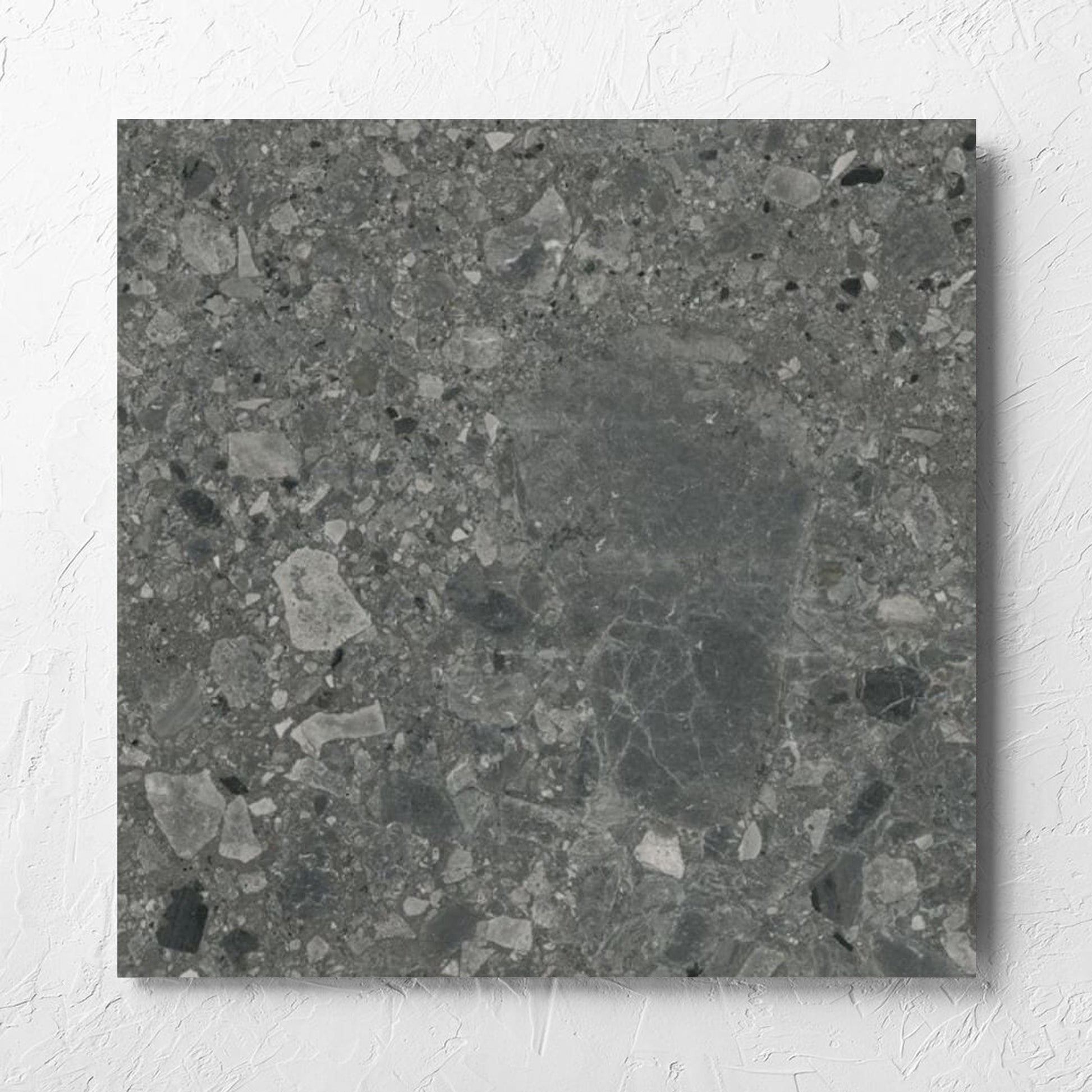 Ceppo Nero InOut 600x600mm tile laid flat on a white rendered wall, showing the tile surface