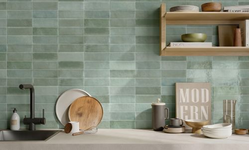 Chroma Celadon Gloss 52x160mm tiles installed as a kitchen splashback in sage green, styled with open timber shelving, a black faucet, and modern kitchenware.