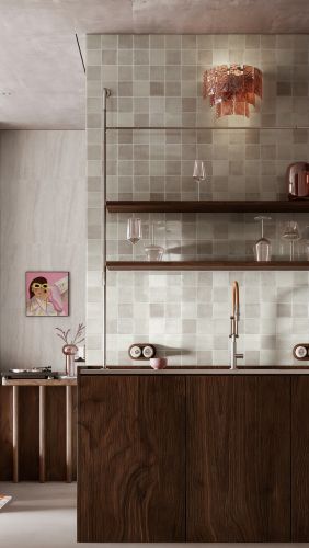 Chroma Gris Gloss 100x100mm tiles covering a kitchen splashback and bar area with dark timber cabinetry, open shelving, and a copper wall sconce.