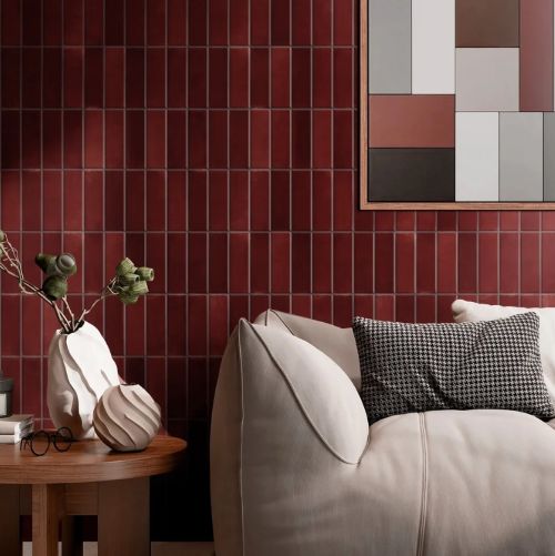 Chroma Rosso Matt 52x160mm deep red rectangular tiles covering a living room feature wall styled with a cream sofa and ceramic vases.