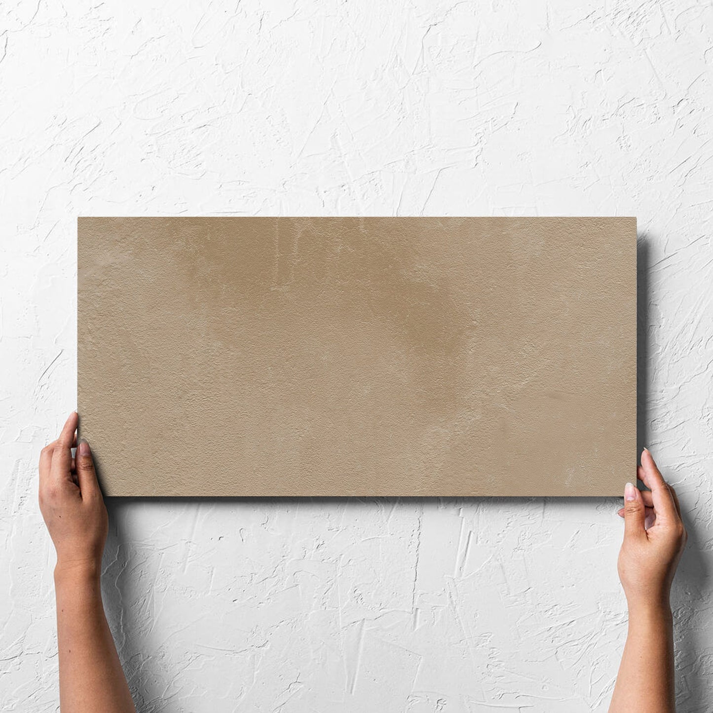 Hand holding a single Clay Orvieto Light Terracotta 300x600mm tile against a white rendered wall, showing the matt surface