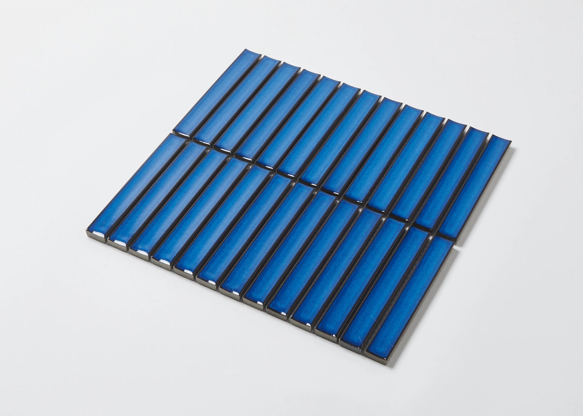 A sheet of Cobalt Blue Gloss Concave Porcelain Glazed Finger 20x145mm tiles arranged in a staggered brick pattern with dark grout on a white background.
