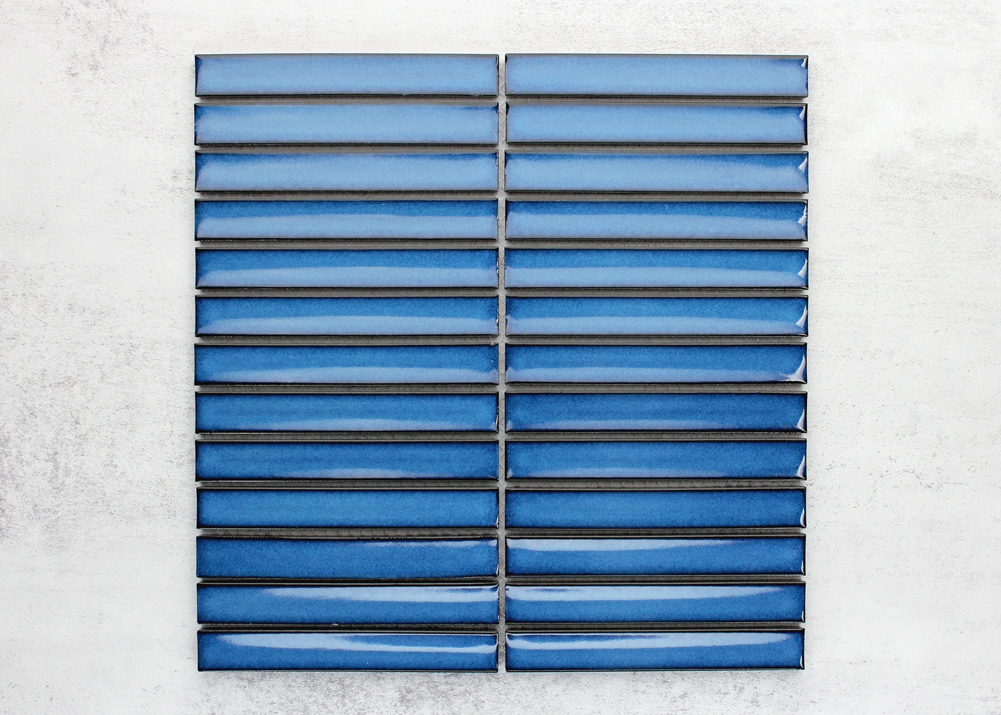 Pack shot of Cobalt Blue Gloss Concave Porcelain Glazed Finger 20x145mm tiles arranged in a stacked horizontal grid showing glossy concave surface and rich blue glaze variation.