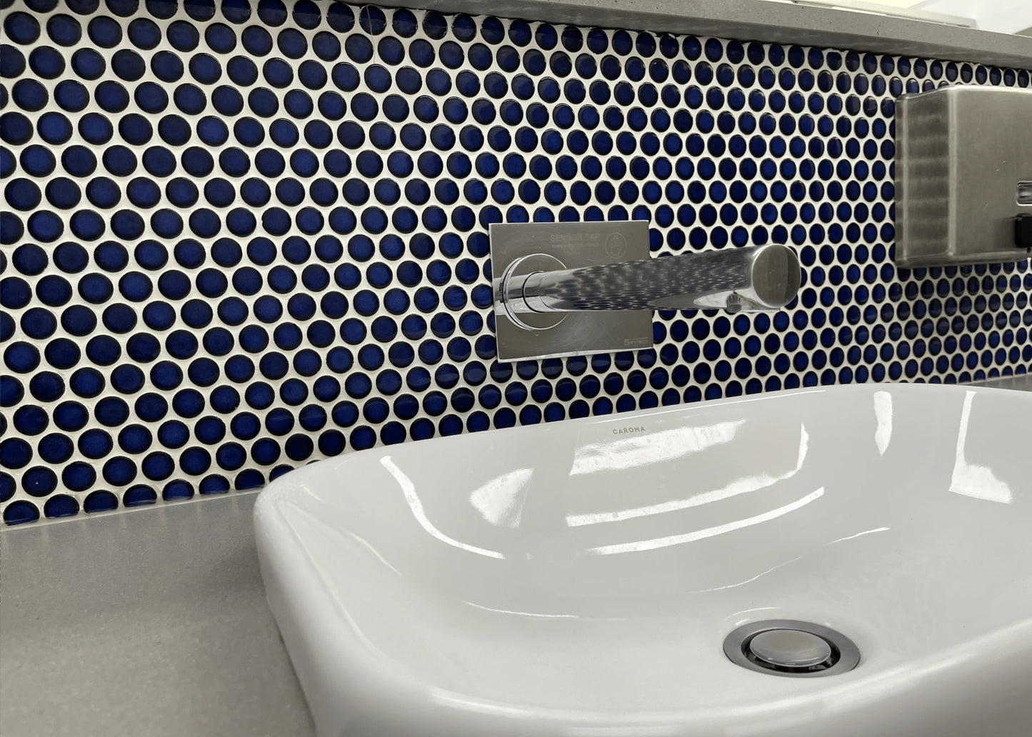 Cobalt Blue Gloss Diameter Glazed Porcelain Penny Round 19mm tiles installed as a bathroom feature wall behind a white Caroma vessel basin with chrome wall-mounted tapware.