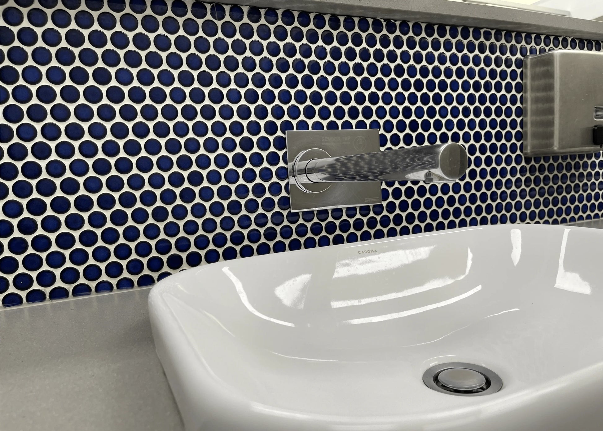 Cobalt Blue Gloss Diameter Glazed Porcelain Penny Round 19mm tiles installed as a bathroom feature wall behind a white Caroma vessel basin with chrome wall-mounted tapware.