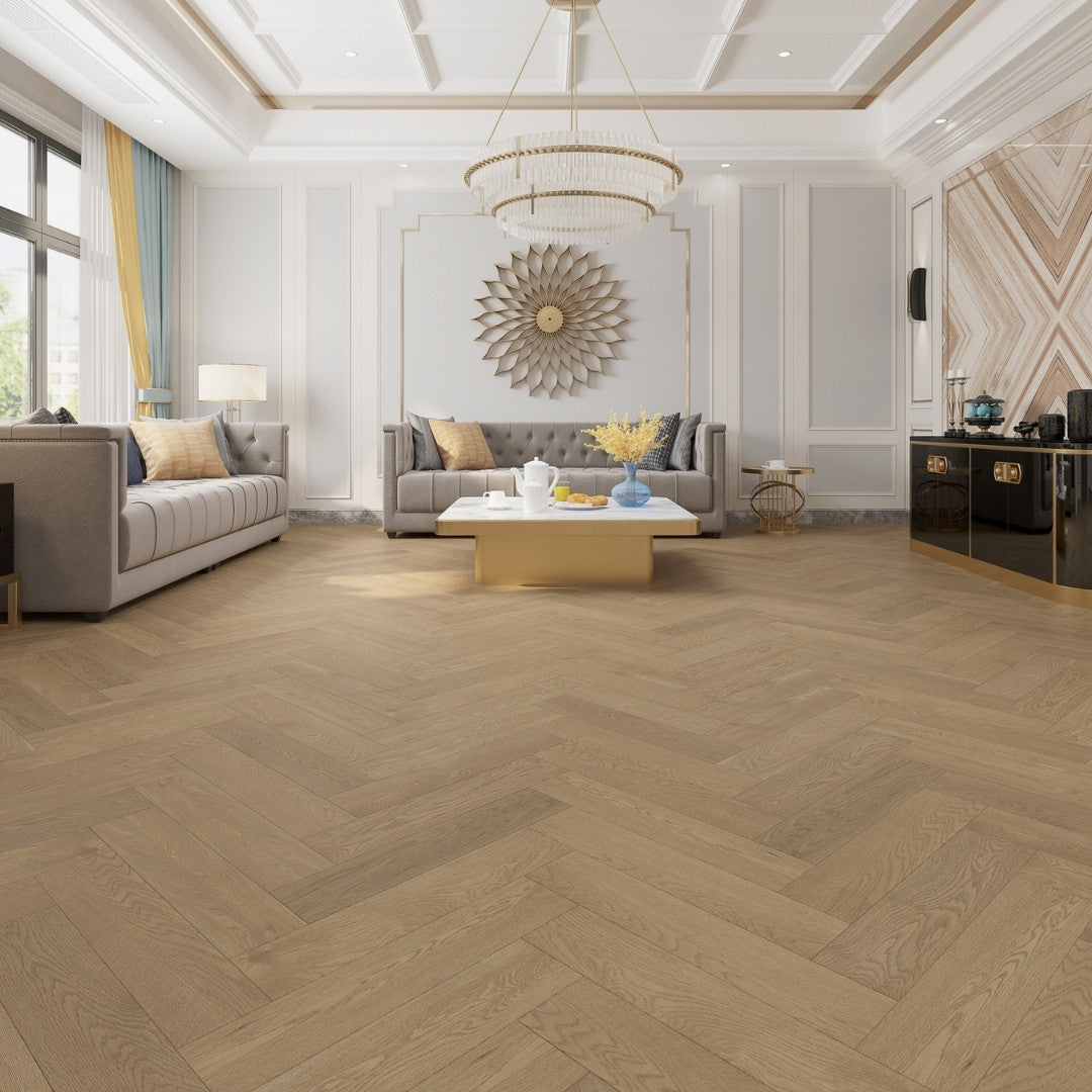 Coral Sand iDesign Herringbone Flooring 15/3mm installed in a luxurious living room featuring a crystal chandelier, tufted grey sofas, and gold accents.
