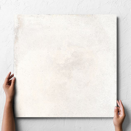 Hand holding a single Cotto Ice Matt 600x600mm tile against a white rendered wall, showing the matt surface