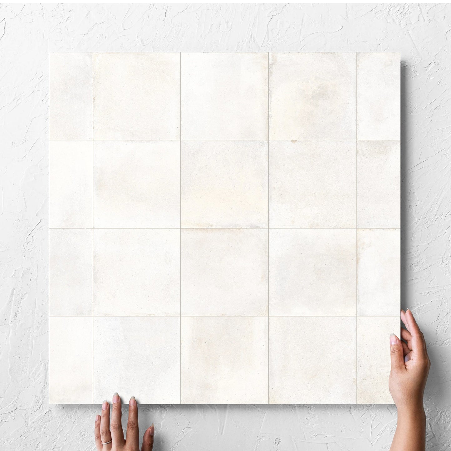 Hand holding a single Cotto Ice Matt 600x600mm tile against a white rendered wall, showing the matt surface