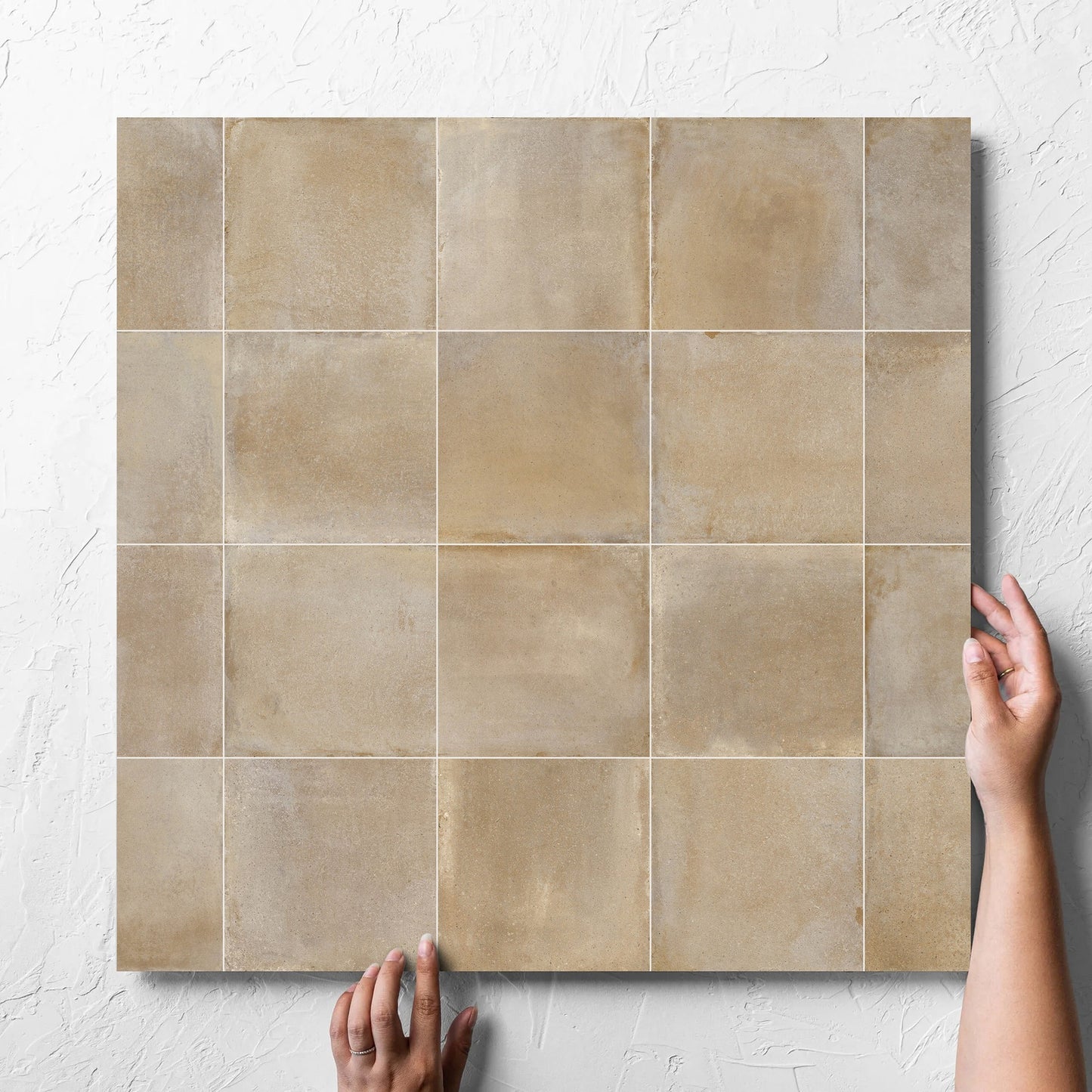 Hand holding a single Cotto Siena Matt 600x600mm tile against a white rendered wall, showing the matt surface