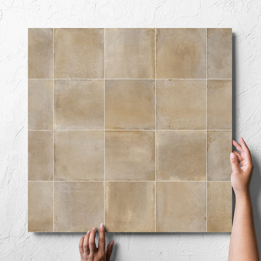 Hand holding a single Cotto Siena Matt 600x600mm tile against a white rendered wall, showing the matt surface