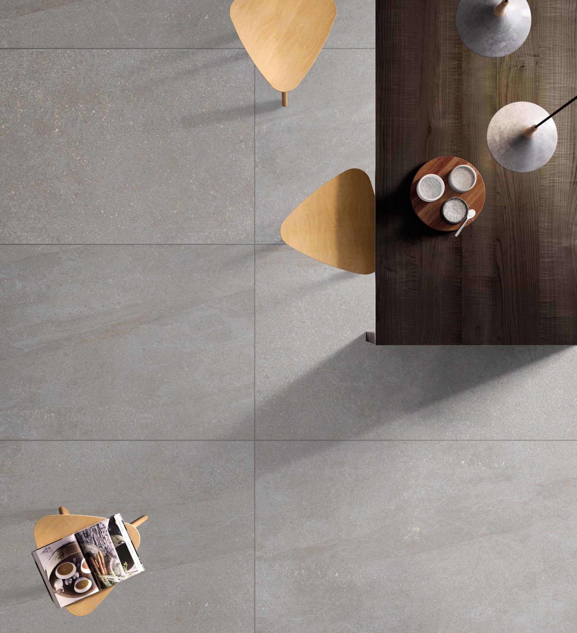 Crystal Quartz Greige Matt Rectified 600x600mm floor tiles installed in a modern dining area, shot from above with a dark wood table, golden chairs, and pendant lights.