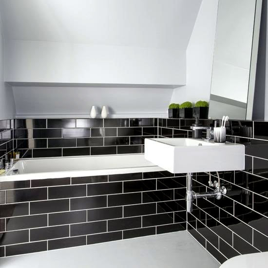 Cucina Black Gloss 100x300mm tiles covering the walls and bath surround of a modern monochrome bathroom with a white wall-mounted basin.