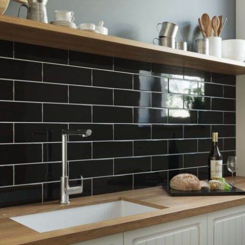Cucina Black Gloss 100x300mm metro tiles installed as a kitchen splashback behind a undermount sink, paired with warm wood worktops and open shelving.