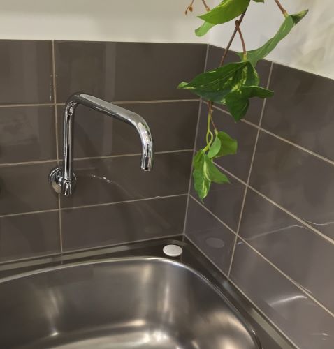 Cucina Caffe Gloss 100x300mm dark brown glossy wall tiles installed as a kitchen splashback behind a chrome tap and stainless steel sink.