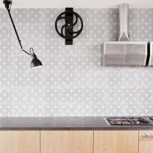 Da Vinci Milano Matt 200x200mm grey cross-pattern wall tiles installed as a kitchen splashback with wooden cabinetry, gas hob, range hood, and industrial black wall lamp.